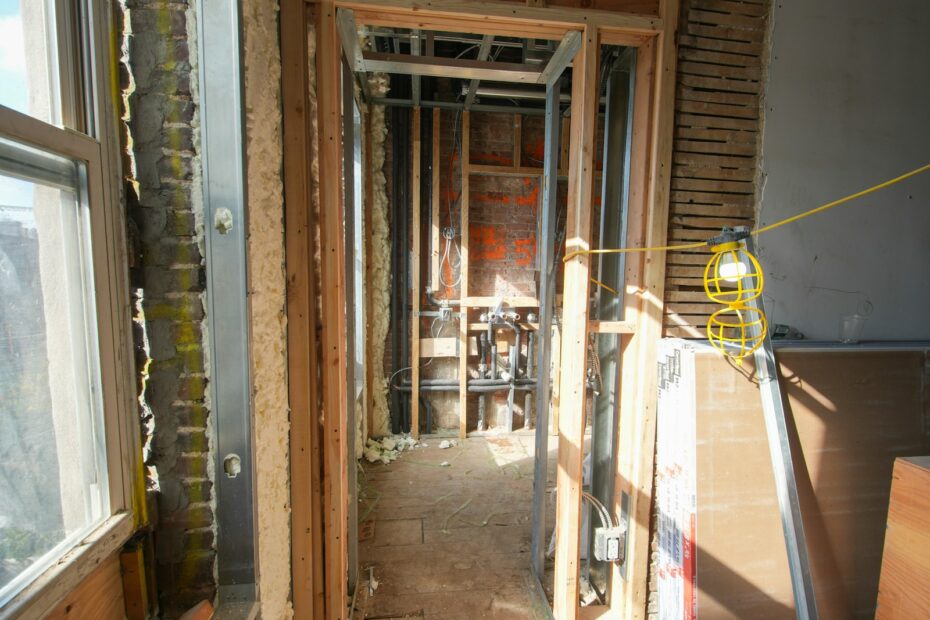 Room under renovation with exposed wood framing and unfinished walls, the stage where DIY vs professional basement finishing decisions matter most