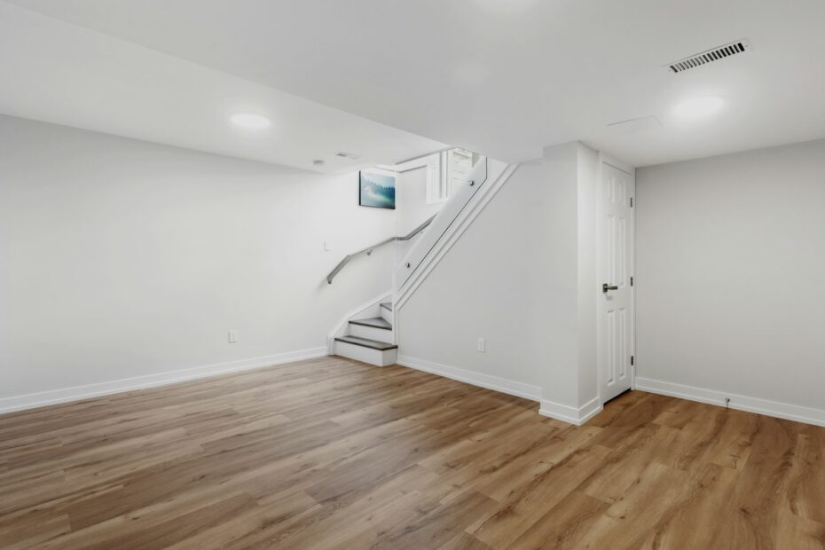Finished basement with staircase, hardwood floors, and recessed lighting, photographed for a real estate listing
