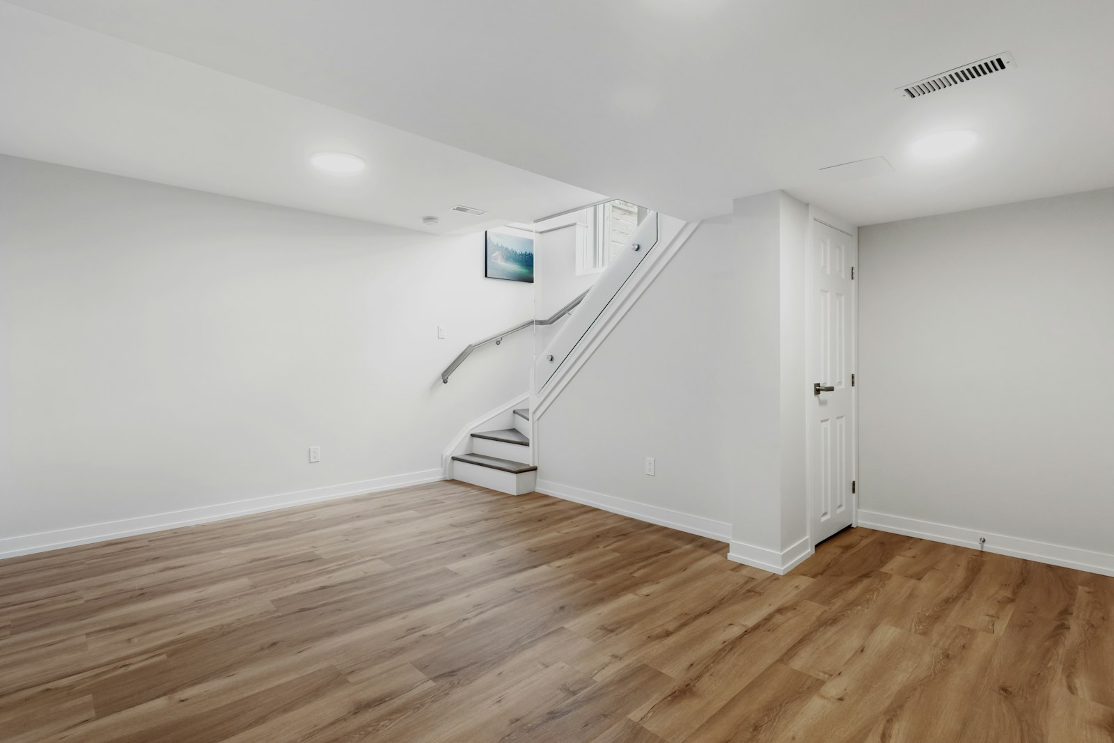 Finished basement with staircase, hardwood floors, and recessed lighting, photographed for a real estate listing